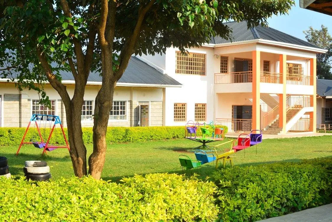 The primary building beside the playground and a shade tree